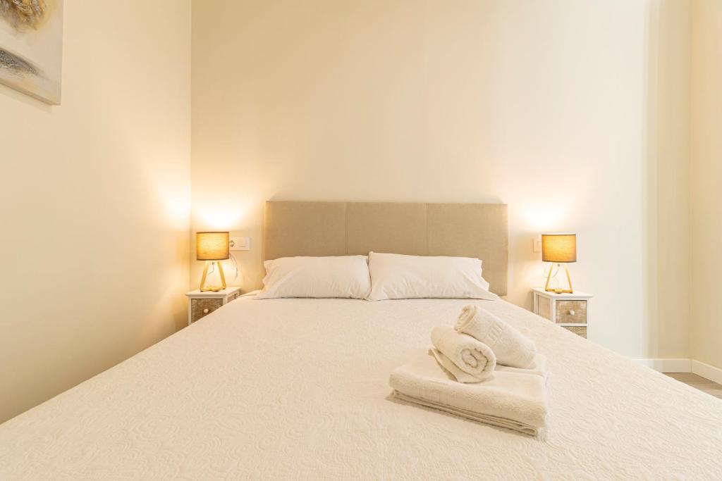 赫雷斯-德拉弗龙特拉Top & Chic Albarizuela Suites - Apartamentos Jerez的卧室配有白色床和毛巾