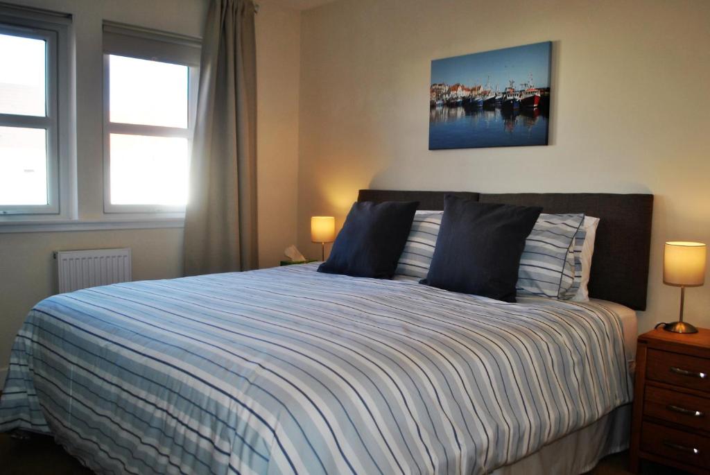 安斯特拉瑟Forth View- stylish upper apartment with sea views的一间卧室配有一张带蓝色和白色棉被的床