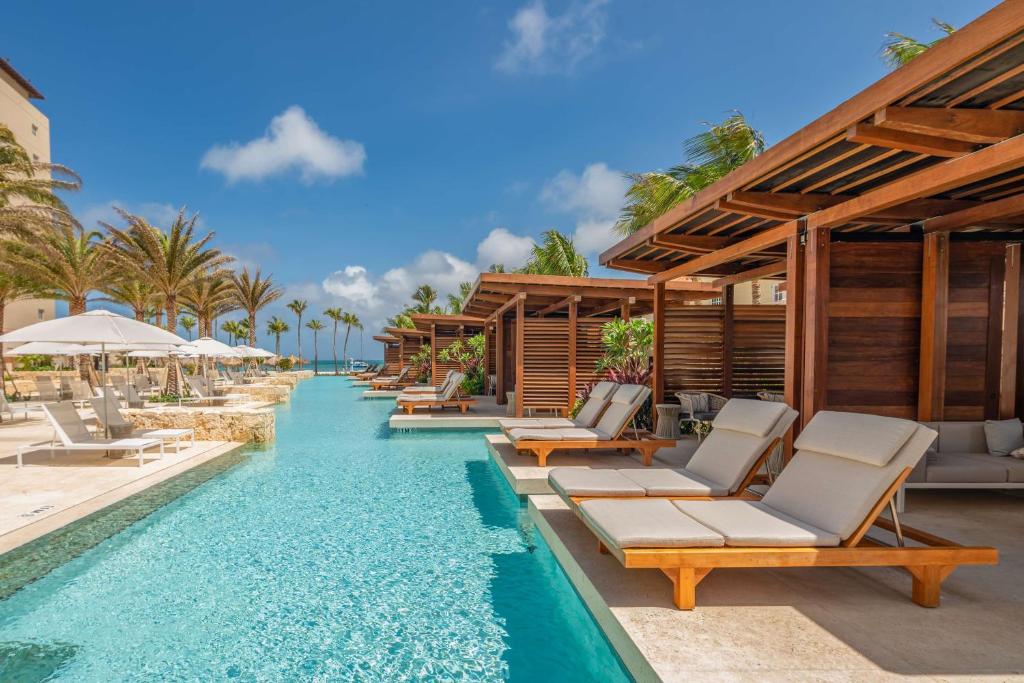 棕榈滩阿鲁巴岛凯悦度假酒店&赌场的一个带躺椅和遮阳伞的度假村无边泳池