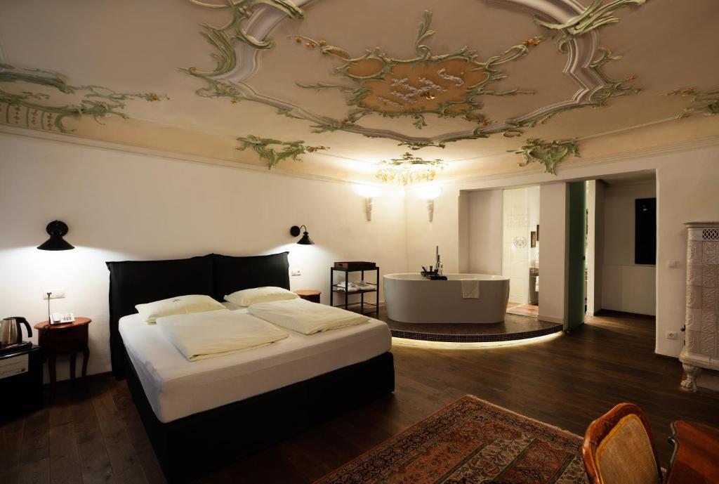 萨尔茨堡卡瑟勒布劳老城区酒店的一间卧室配有一张床,天花板配有浴缸