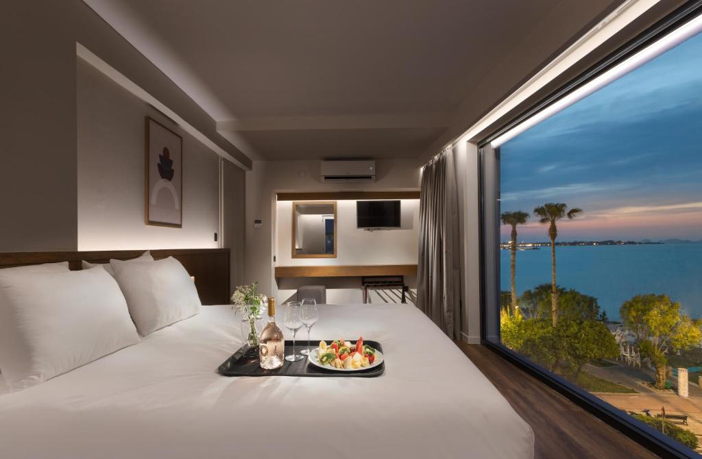 科斯镇Kos Divine Hotel & Suites的酒店客房,在带大窗户的床上用餐