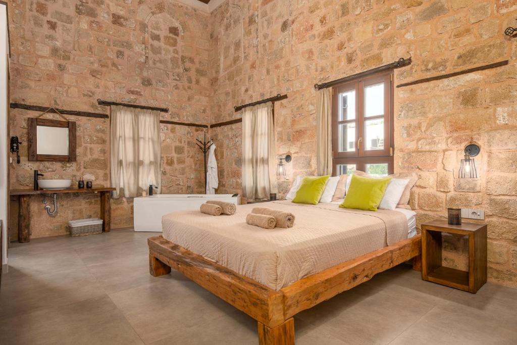 罗德镇Ancient Knights Luxury Suites的卧室设有一张砖墙内的大床
