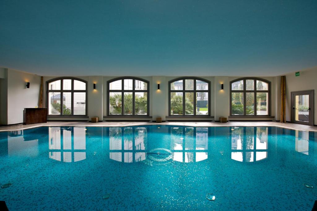 米兰维斯康蒂皇宫豪华酒店的一座大型游泳池,设有窗户,位于大楼内