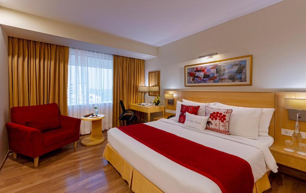新德里Zone Connect by The Park Saket New Delhi的酒店客房设有一张大床和一张红色椅子。