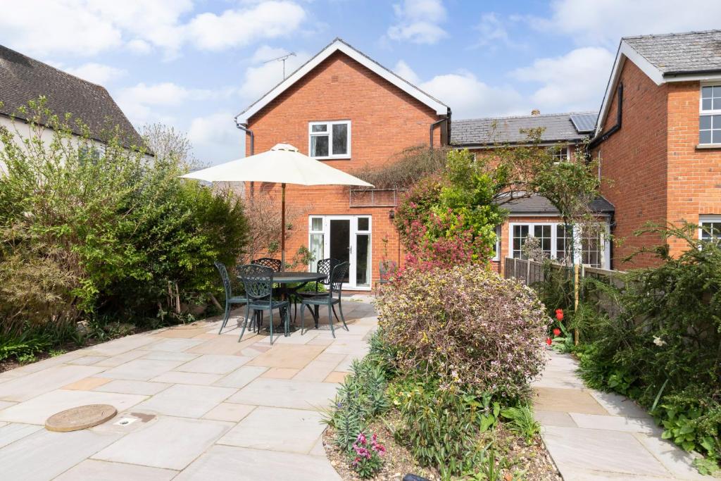 切尔滕纳姆Luxury Cheltenham Home with EV charger - Lechampton Hills的庭院配有遮阳伞和桌椅。