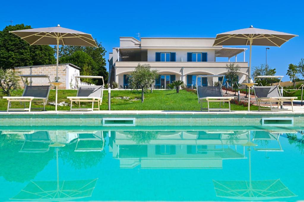 斯蓬加诺Terra Home Resort的房屋前的游泳池配有椅子和遮阳伞