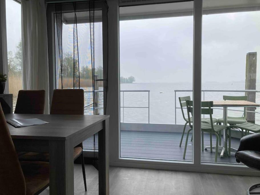 比丁赫伊曾Houseboot Cormorant, lake view的一间带桌子的客厅和一个阳台