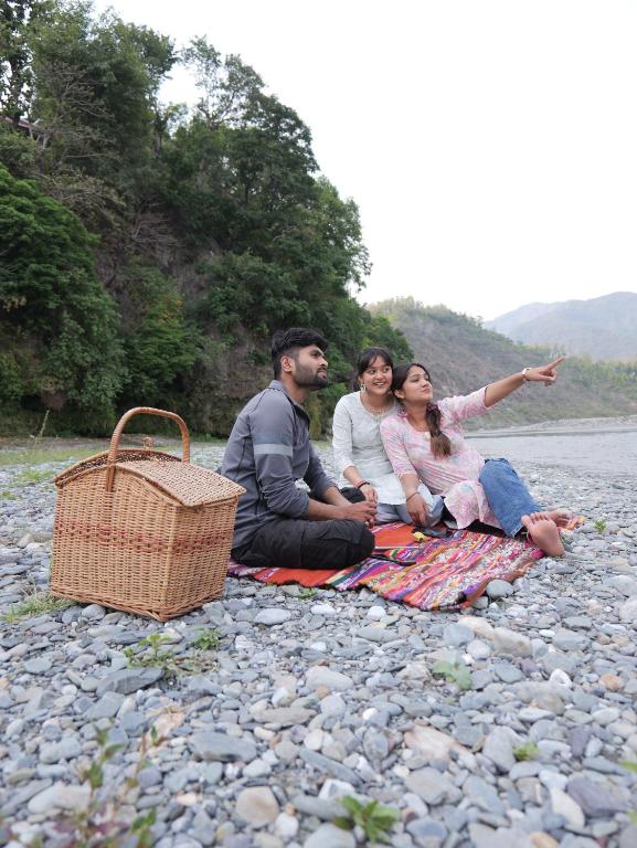ChūharpurSukoon - A Wellness Resort, Uttarakhand的三人坐在岩石上的毯子上