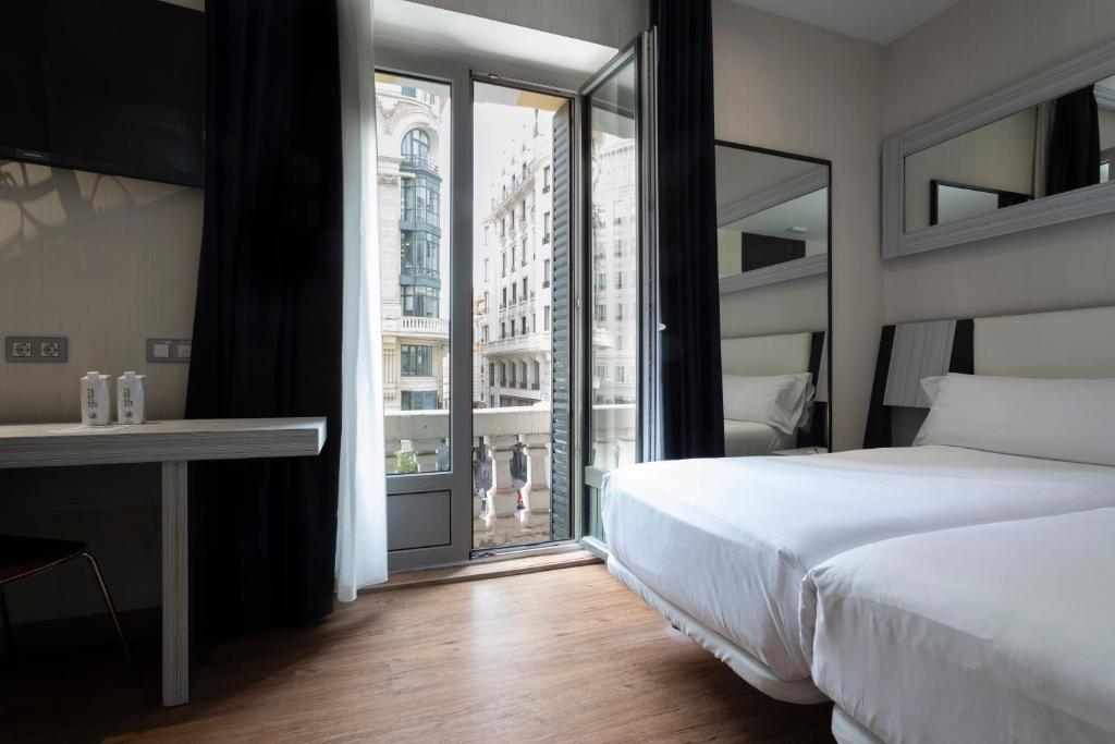 马德里珀蒂宫翠柏酒店的一间卧室设有一张床和一个大窗户