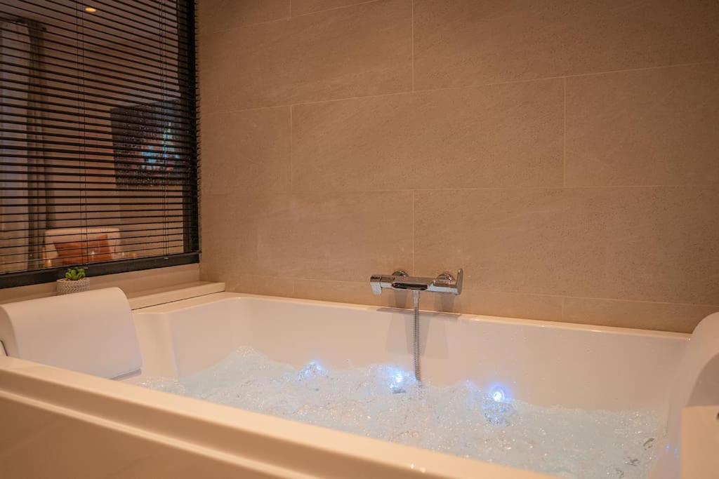科洛布里埃Suite de Luxe Jacuzzi balnéo,King size Bed的装满水的浴缸,配有水龙头