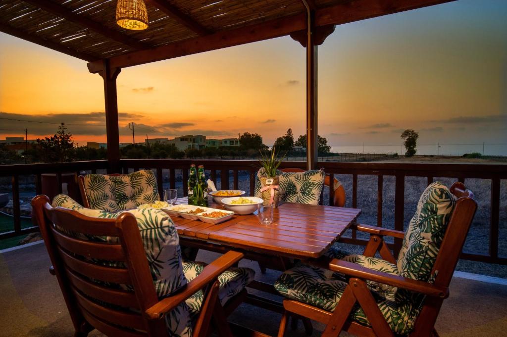 古瓦伊Mayia Sunset sea front house Gouves Heraklion的甲板上的木桌和椅子,享有日落美景