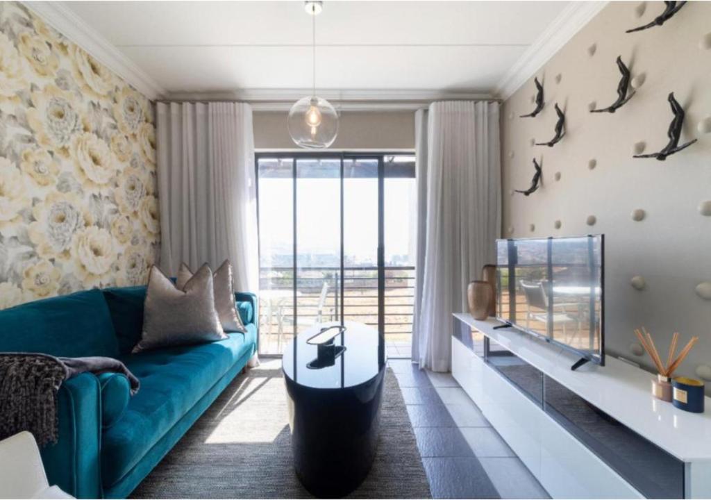 约翰内斯堡The Steynview Apartment - Fourways Sandton的客厅设有蓝色的沙发和大窗户