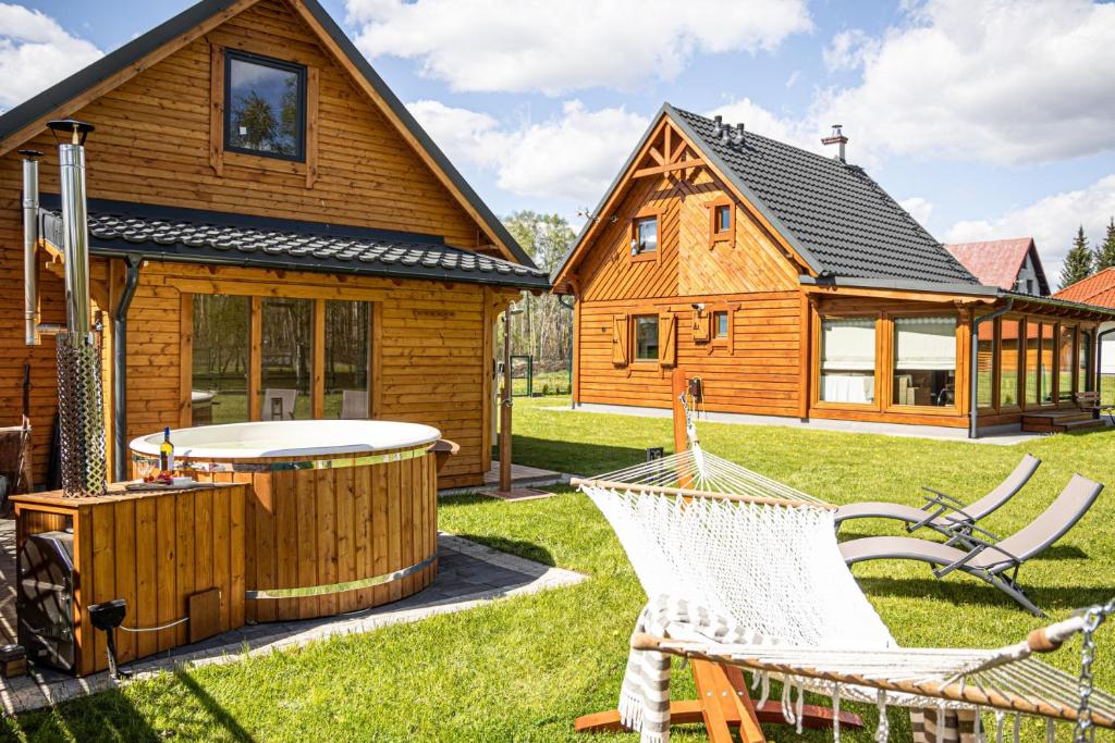 IdzbarkUroczysko Lubajny的小木屋设有热水浴池和庭院内的椅子