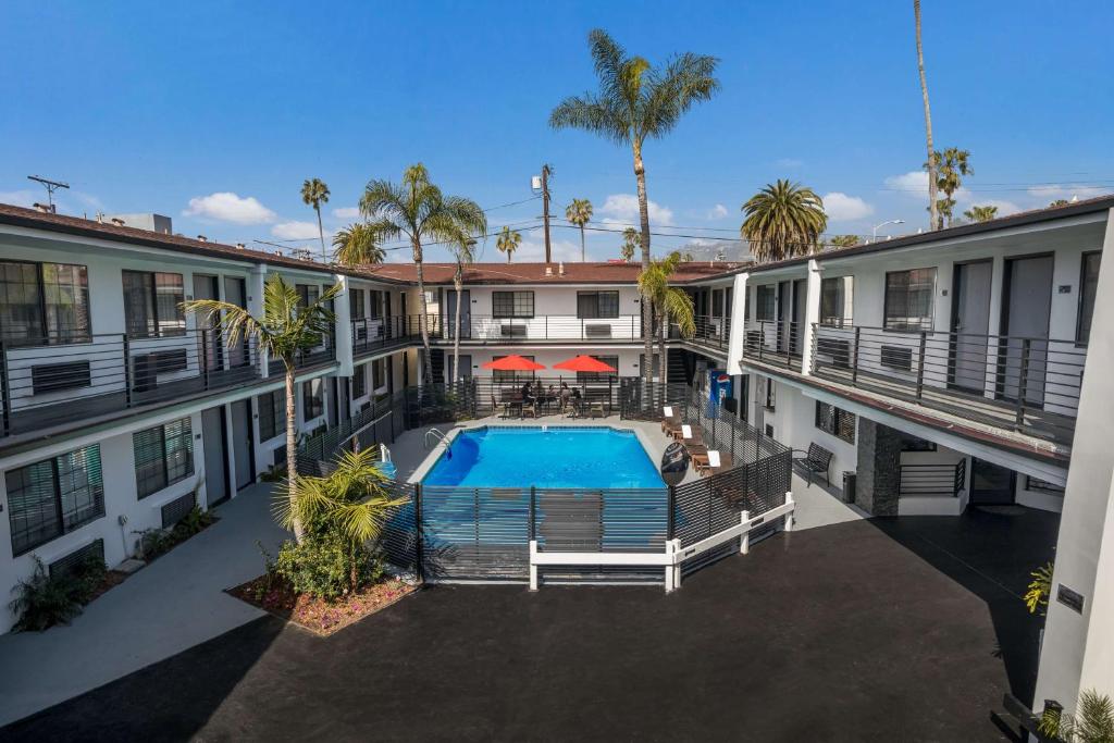 洛杉矶Sunset West Hotel, SureStay Collection By Best Western的公寓大楼设有游泳池和棕榈树