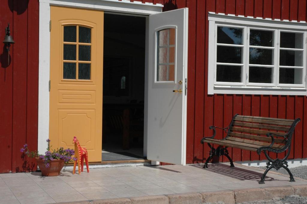 BrokindSundsmåla Landsbygdshotell的红色建筑旁的长凳,有黄色的门