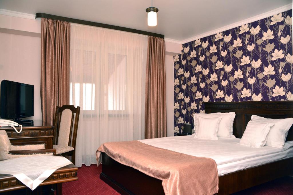 萨图马雷Hotel President的一间卧室配有一张带花卉壁纸的床