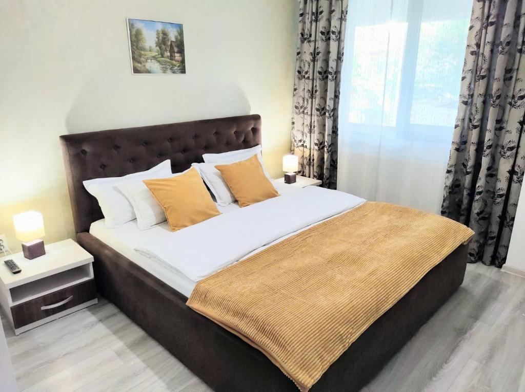 雅西Simona Apartament Palas Mall 1的一间卧室配有带白色床单和橙色枕头的床。
