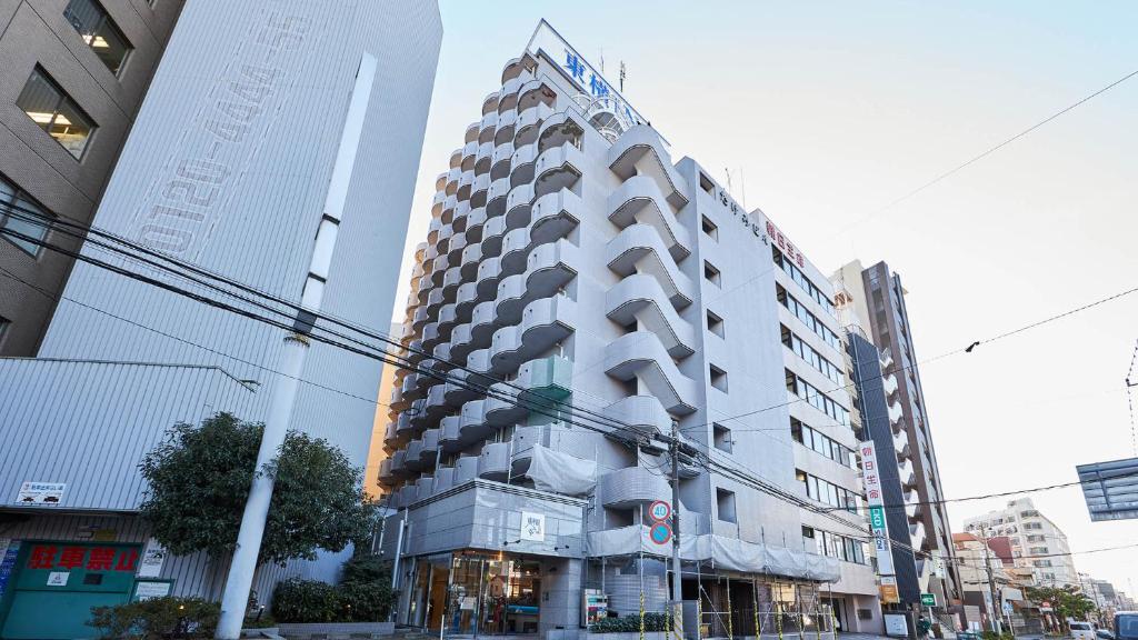 船桥市Toyoko Inn Tsudanuma-eki Kita-guchi的一条城市街道上高大的白色建筑