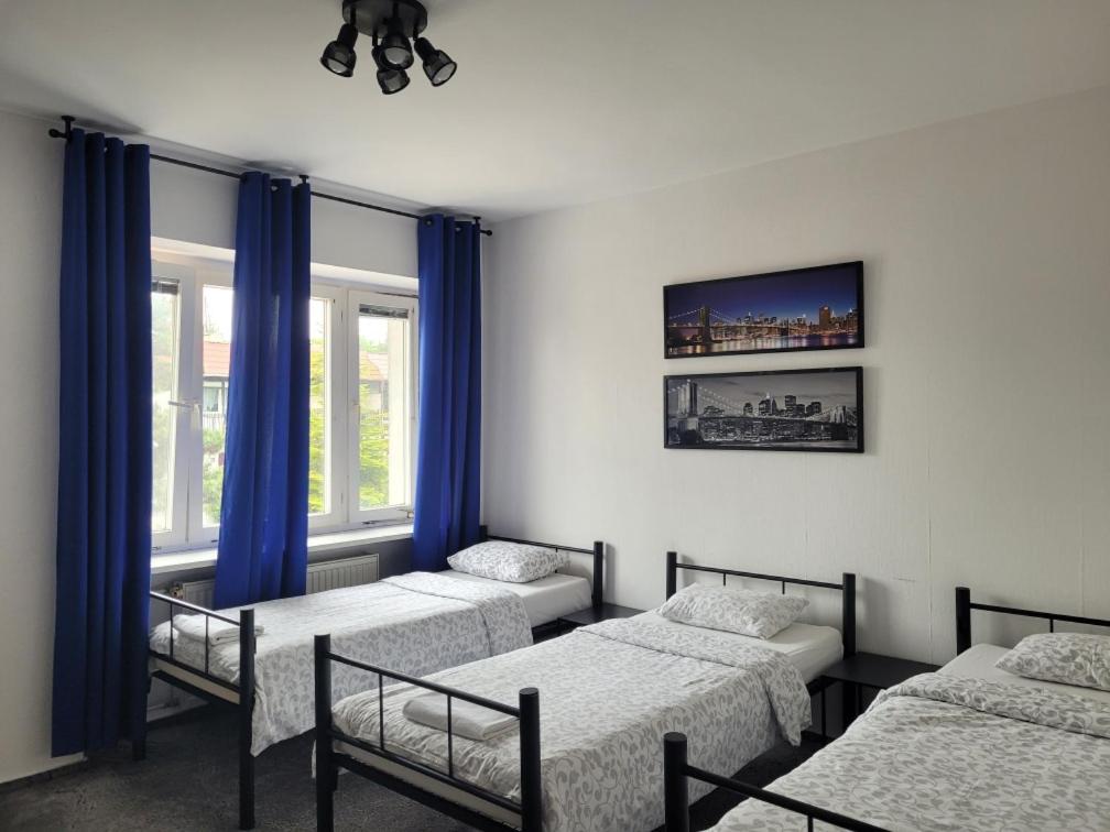 波兹南Miastkovo的一间设有四张床、蓝色窗帘和窗户的客房