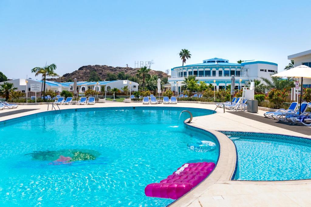 迪巴Holiday Beach Resort的度假村内带躺椅和椅子的游泳池