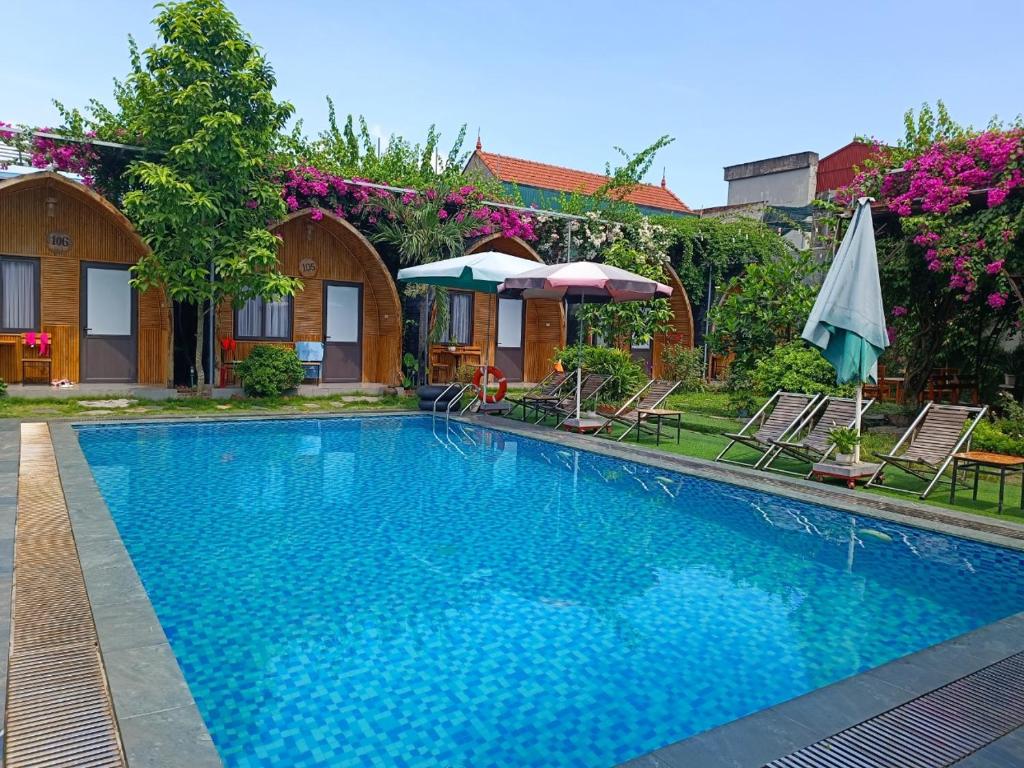 宁平Tam Coc Village Bungalow的房屋旁的游泳池配有椅子和遮阳伞