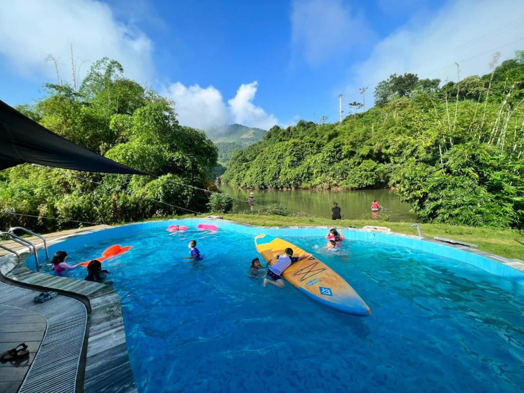 和平Caofong Glamping Village的一群人在游泳池里,那里有冲浪板
