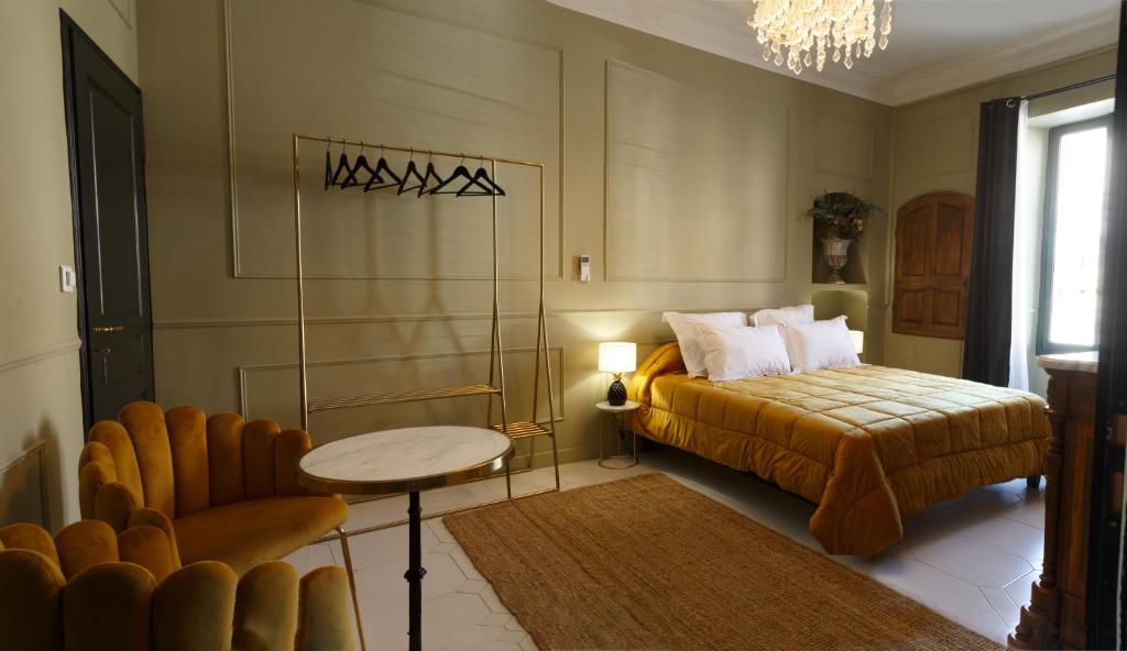 卡瓦永Le 215 Gambetta boutique hôtel en Provence的卧室配有1张床、1张桌子和1把椅子