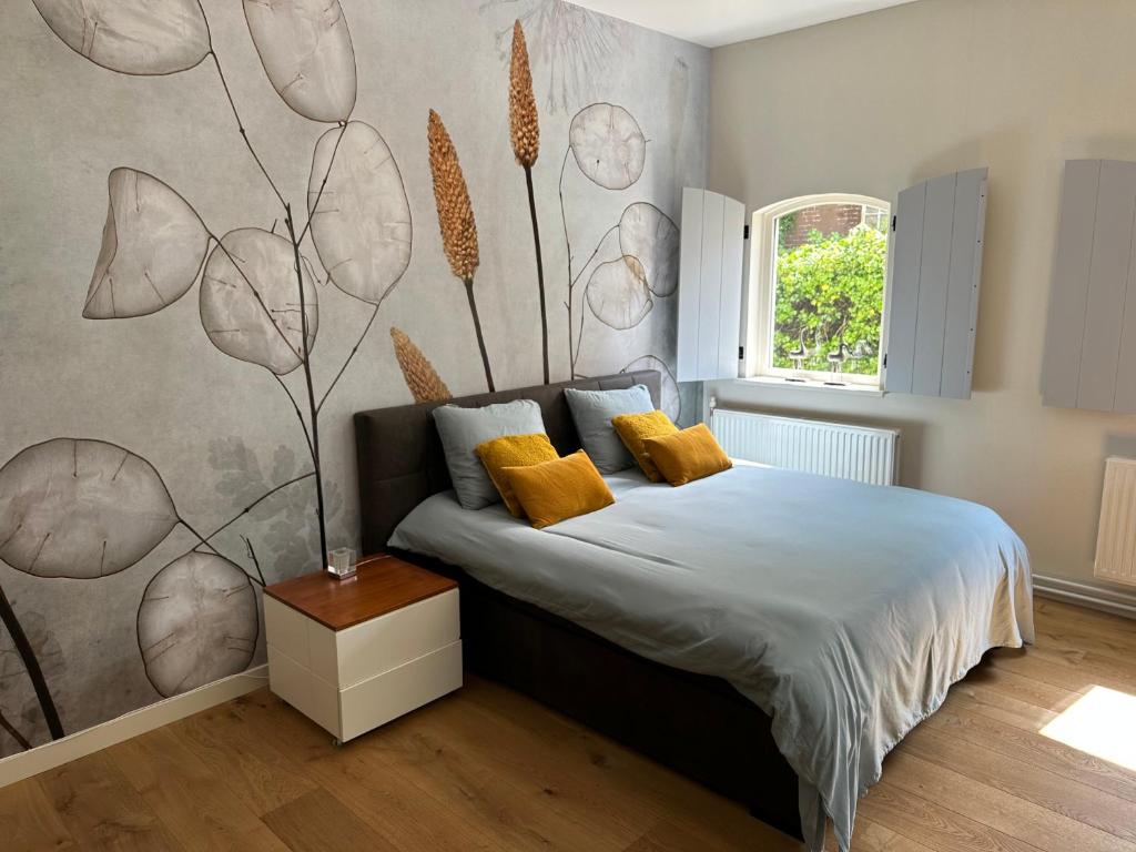 TynaarloKoetshuys van Villadelfia的一间卧室配有一张床和一堵带花卉壁画的墙壁