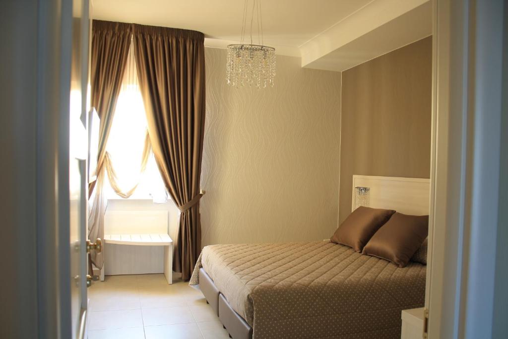 格拉维纳普利亚B&B Colle del Re的一间卧室设有一张床、一个窗户和一个吊灯。
