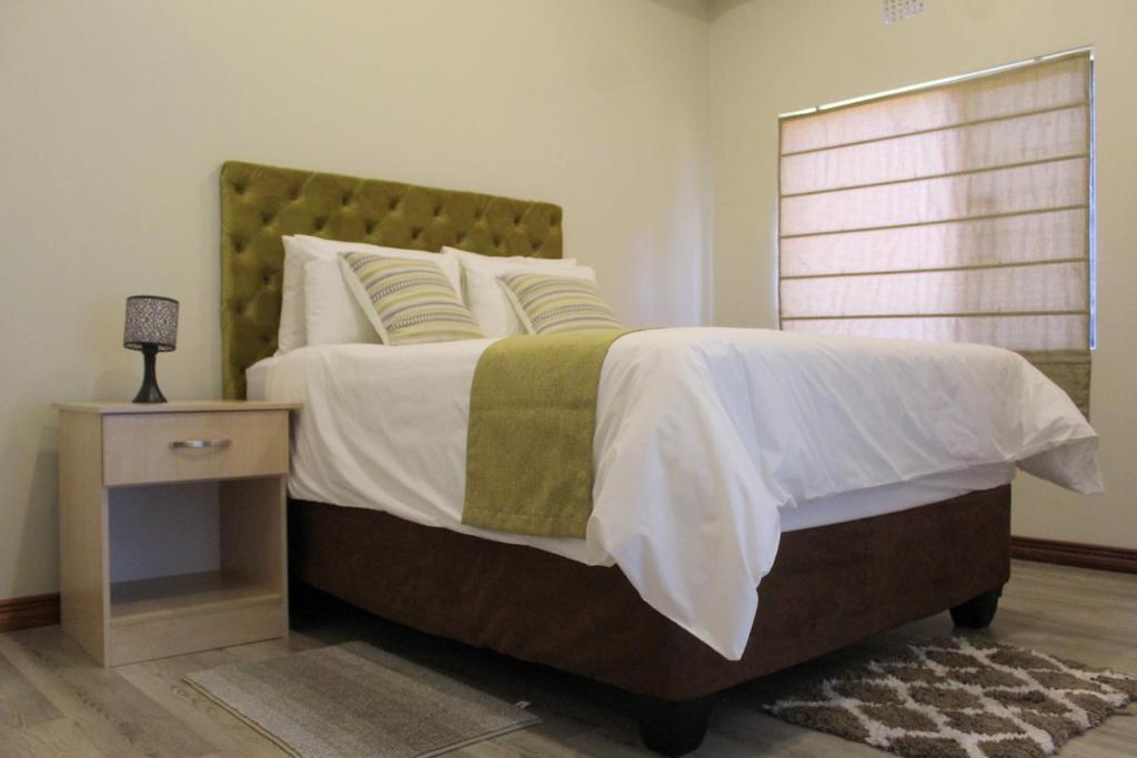 哈博罗内Staybridge Golfview Suites的一间卧室配有一张大床和一个床头柜