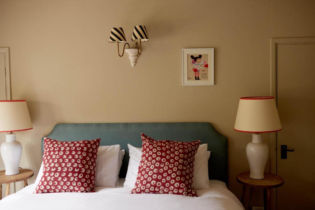 布罗德绰克The Queen's Head的一间卧室配有一张带红色枕头的床和两盏灯。