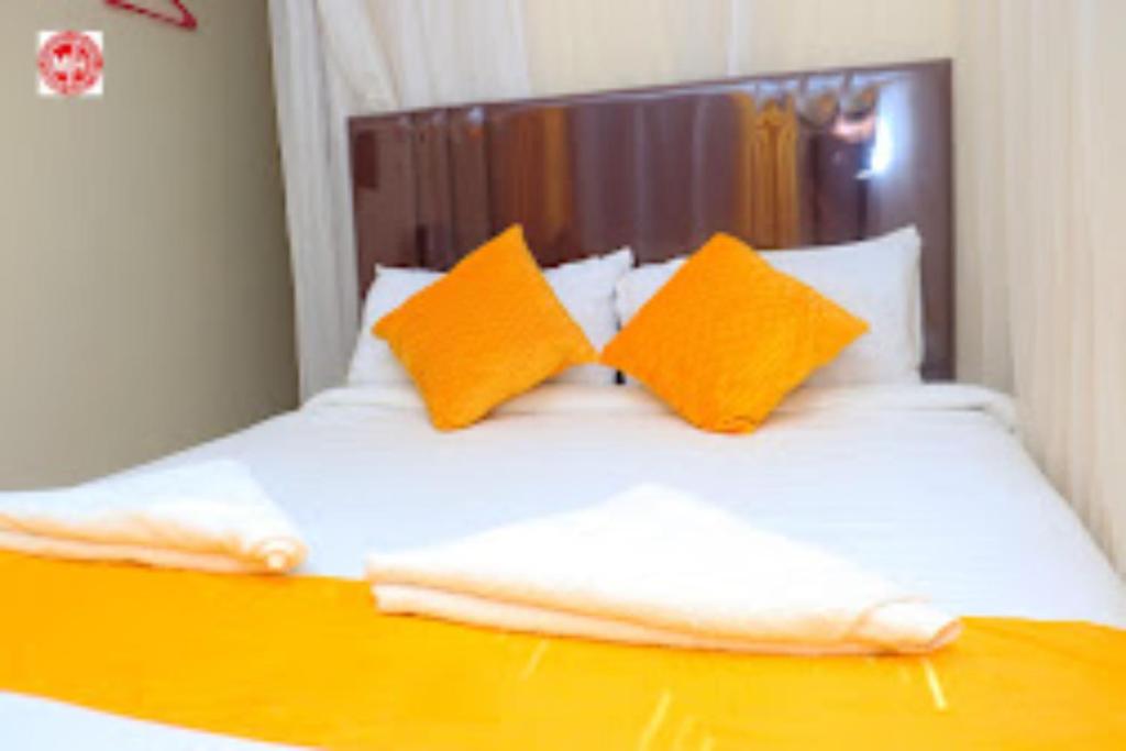 马查科斯Machakos Inn Hotel的一张带橙色和白色枕头的床