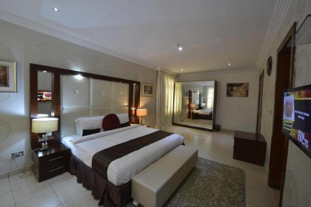 IkuataPalazzo Dumont Hotel的一间大卧室,配有一张大床和一台电视
