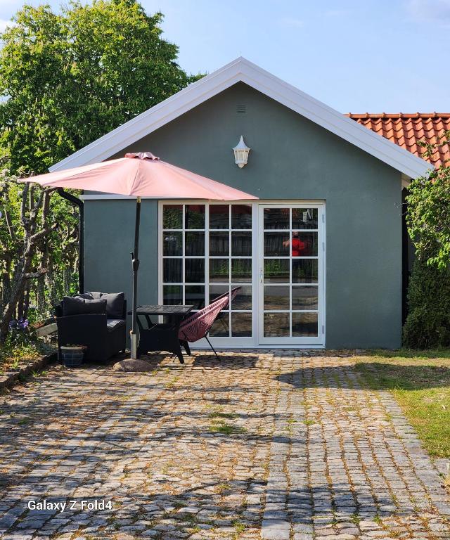 锡姆里斯港ÖSTERLEN PARKEN的房屋设有带雨伞和桌子的庭院