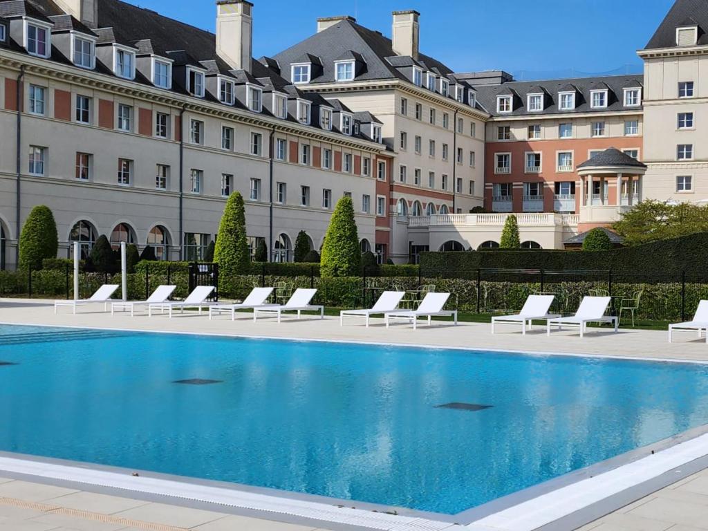 马尼库尔勒翁格尔Dream Castle Hotel Marne La Vallee的一座带白色躺椅的建筑前的游泳池