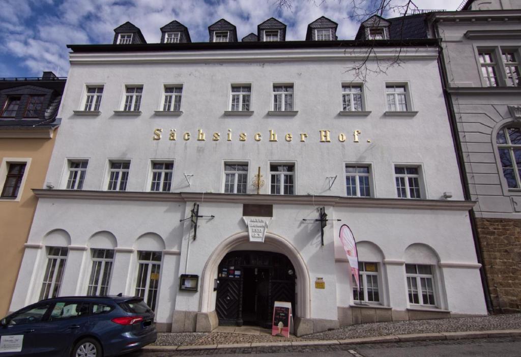 ScheibenbergHotel Sächsischer Hof的一座白色的建筑,上面有草棚屋