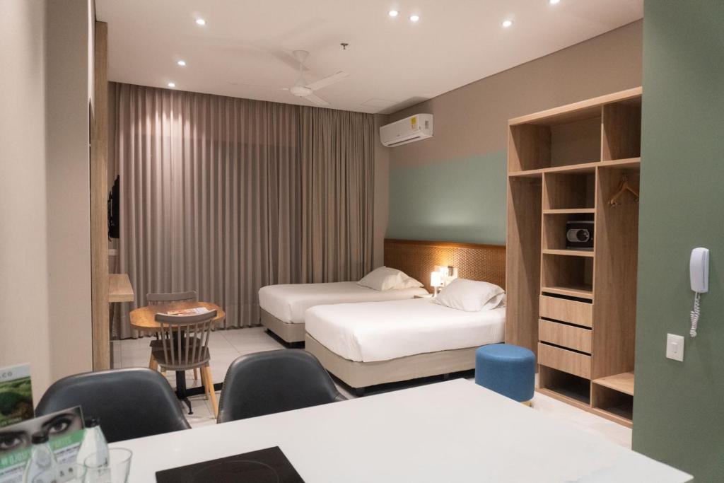 伊瓦格FR Hotel的酒店客房带两张床和一张桌子以及椅子。