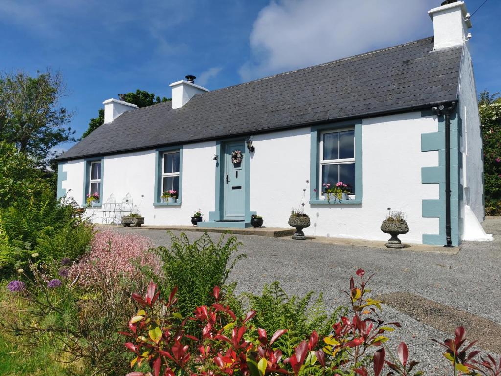 多尼戈尔New Listing - Ladybird Cottage - Donegal - Wild Atlantic Way的白色小屋,设有蓝色门
