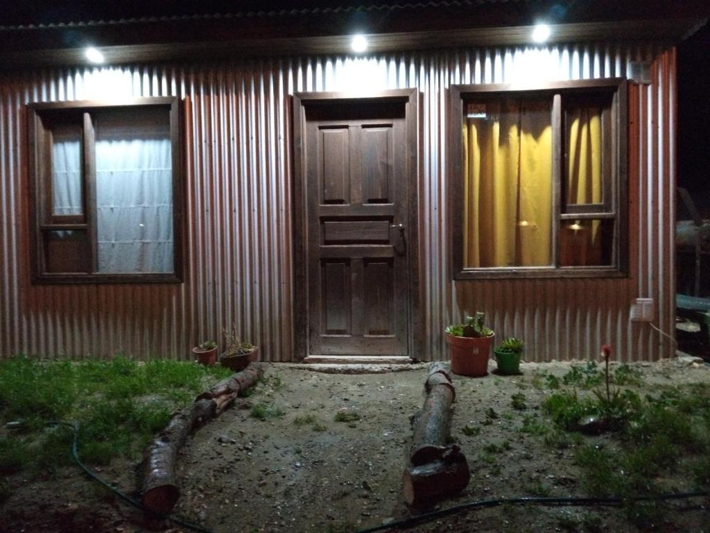 克曼丹特鲁斯皮耶德拉布纳Cabaña La Guanaca的一座房子,晚上有木门和窗户