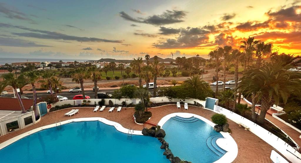 圣米格尔德阿沃纳Suite Poseidon Golf & Ocean View的享有日落的度假村游泳池景致
