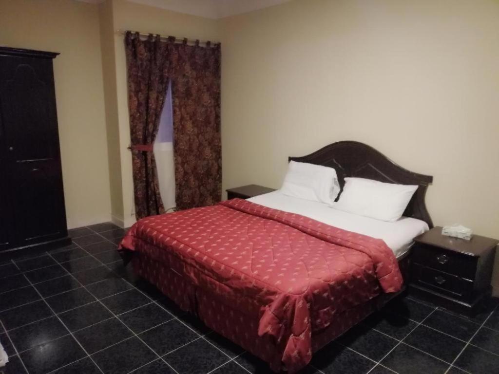 达曼مزايا هاوس的一间卧室配有一张带红色毯子的床和窗户。