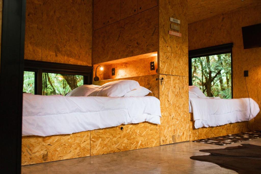 圣弗朗西斯科-迪保拉Cabana na Serra Gaúcha - Refúgio de São Chico的一间卧室配有两张床、白色床单和窗户。