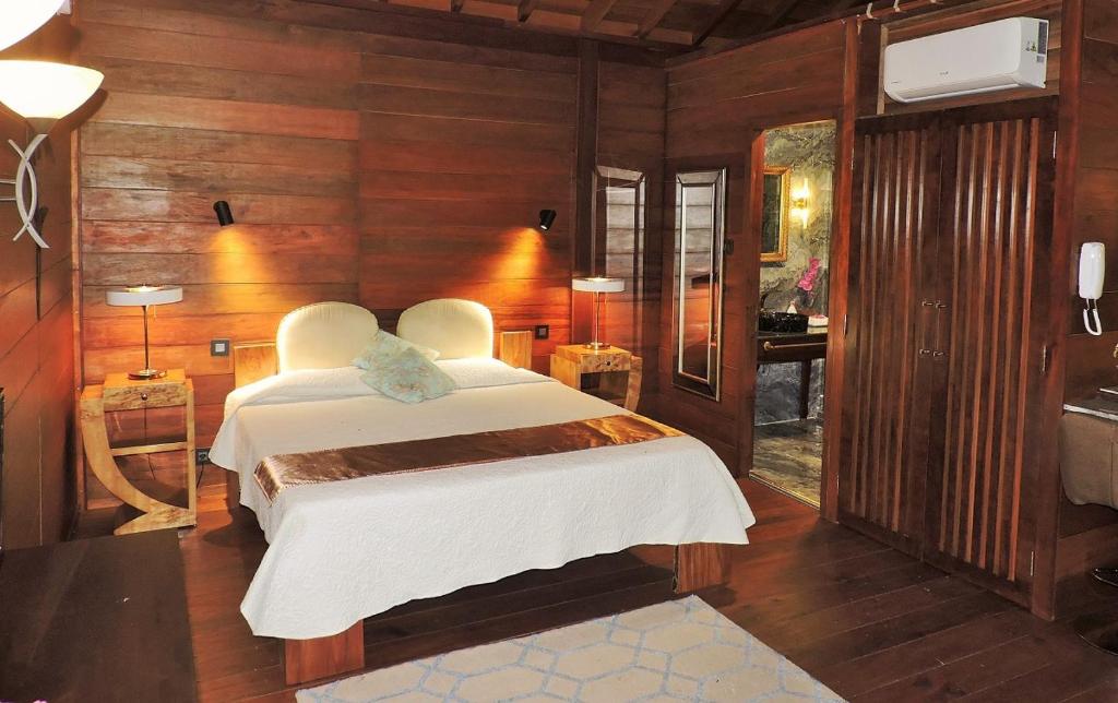 马埃岛Bois Joli的卧室配有一张床铺,位于带木墙的房间内