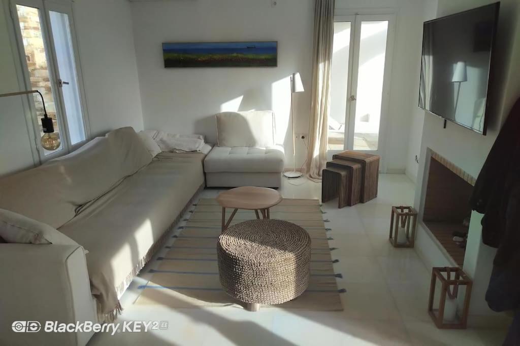 伊奥斯乔拉Cyclades, villa surplombant la mer的客厅配有沙发、椅子和桌子