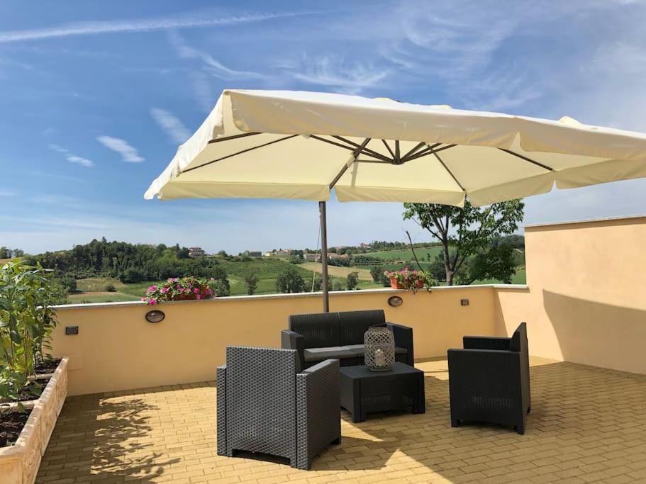 Rosignano MonferratoCa' dal Bertu - Cascina in Monferrato的庭院配有遮阳伞、椅子和桌子。