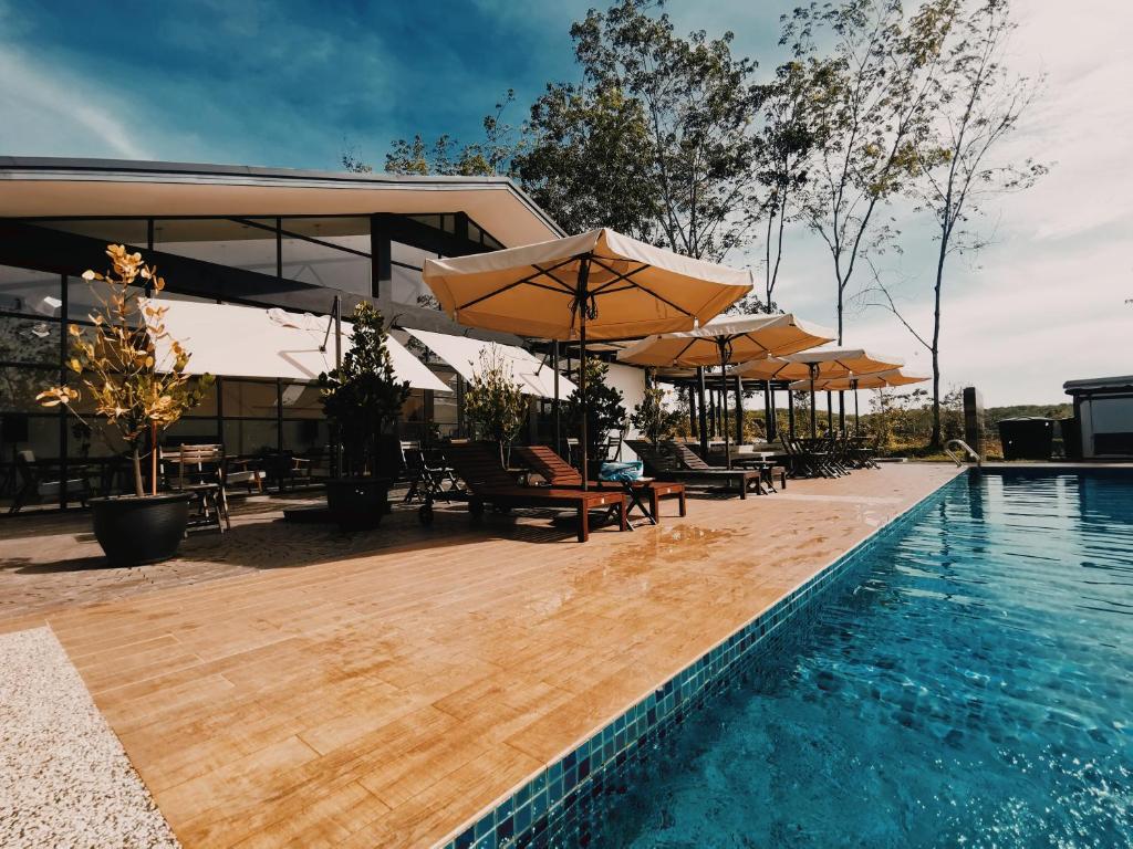 马六甲The Rubber Escape, Melaka的一座游泳池旁设有遮阳伞和桌椅