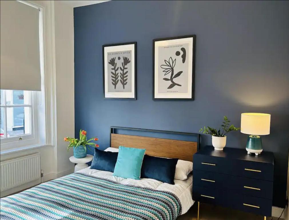 伦敦Gorgeous split level Belsize Park Apartment的一间卧室设有蓝色的墙壁、一张床和一个梳妆台