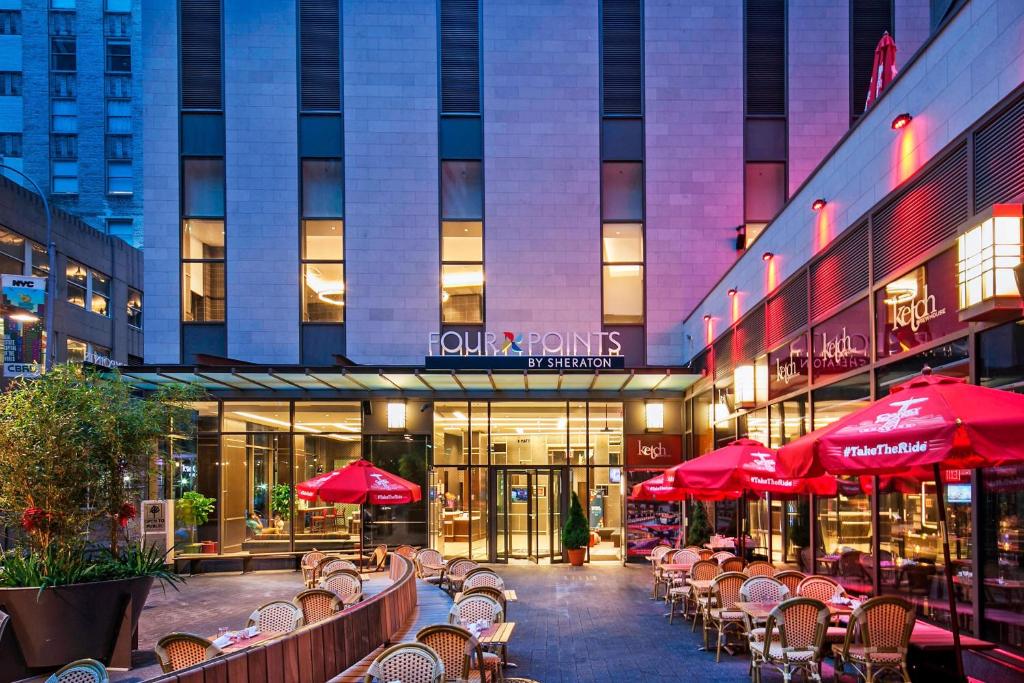 纽约纽约市区福朋喜来登酒店的大楼前的一间餐厅,配有红色遮阳伞