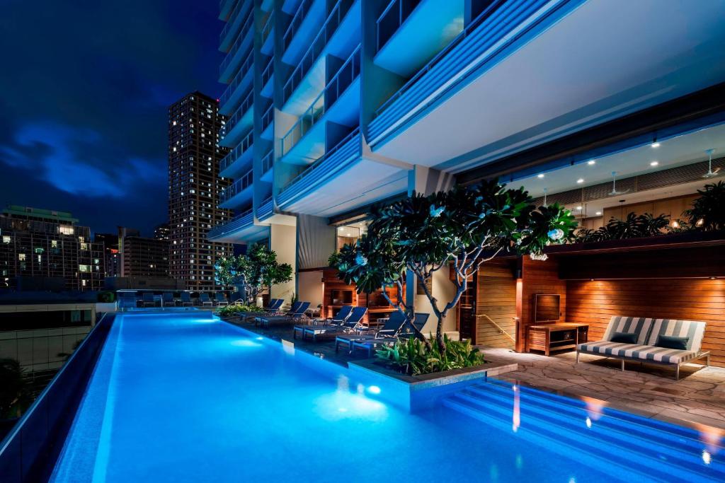 檀香山威基基海滩丽思卡尔顿公寓式酒店的夜间在建筑物屋顶上的游泳池