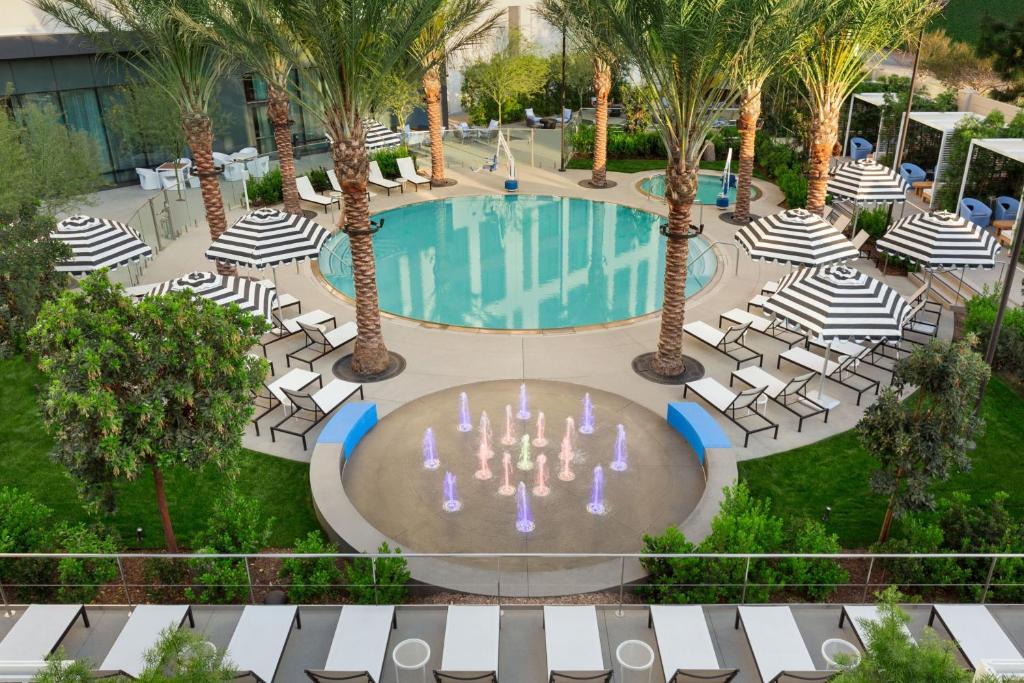 安纳海姆The Viv Hotel, Anaheim, a Tribute Portfolio Hotel的享有带椅子和棕榈树的游泳池的顶部景致